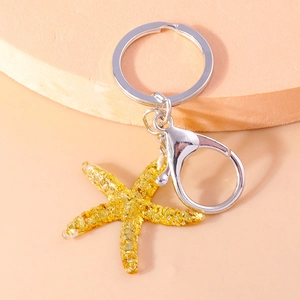 Macro shot of a yellow glitter starfish pendant with silver metal keyring and lobster clasp