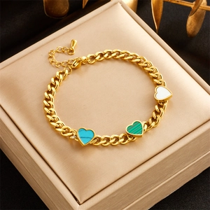 Dettaglio del bracciale in titanio dorato con ciondoli a cuore blu, verdi e bianchi in scatola