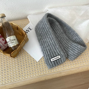 Detail showing the gray knitted scarf texture with a KN STUDIO woven brand label