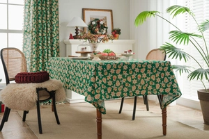 Detail view of festive green tablecloth featuring gingerbread man and Christmas tree patterns