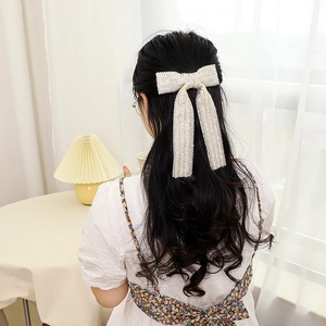 Detailed view of handmade pearl beaded bow hair clip worn in a ponytail hairstyle
