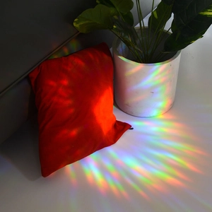 Rainbow prism light effects on red pillow and white flowerpot from suncatcher film