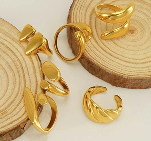Detail view of 18k gold plated stainless steel rings displayed on organic wood slices