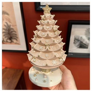 Macro detail of champagne pink Christmas tree music box with gold stars and bows