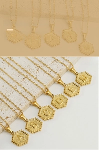 Close-up of golden hexagonal initial pendant with beaded edges and fine link chain