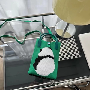 Détail du sac tricoté panda vert montrant la texture, le bouton et la sangle