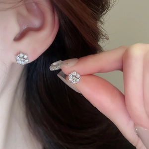 Macro view of sterling silver snowflake earring with zircons worn on model ear