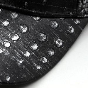 Macro detail of black PU leather baseball cap brim with metallic silver polka dots