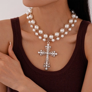 Detail of layered pearl necklace featuring an intricate silver cross pendant with rhinestones