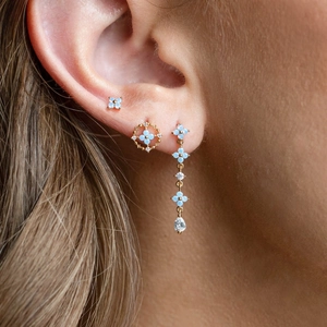 Detail of light blue floral earrings with gold plating and clear teardrop pendants