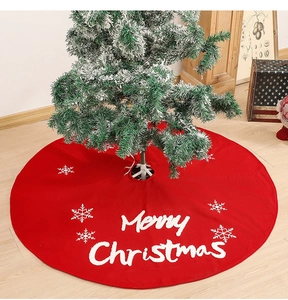 Detail of red Christmas tree skirt with white Merry Christmas embroidery and snowflakes