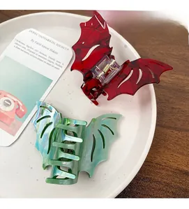 Detail of bat-shaped marble texture hair claws in reddish brown and teal colors
