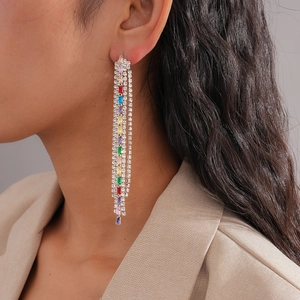 Macro shot of colorful zircon square tassel earrings with sparkling rhinestones on the model