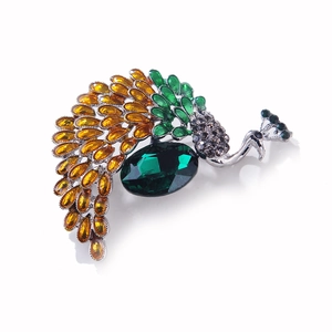 Detail of peacock brooch featuring green crystal center and amber gemstone tail feathers