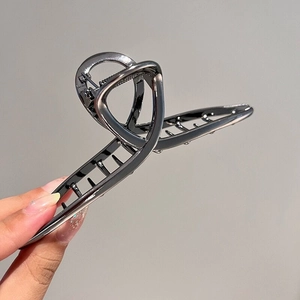 Detailed view of an oversized gunmetal alloy hair claw clip held for size comparison
