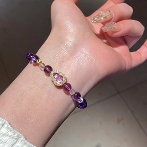 Detail of amethyst beaded snake-wrap bracelet with a rhinestone heart charm on a wrist