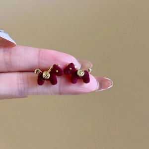 Detalle de pendientes de cachorro en terciopelo rojo oscuro con toques dorados