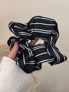 Detail of a large black and white striped scrunchie with a soft glossy satin finish