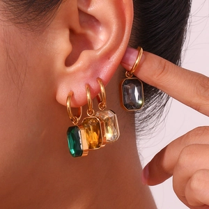 Close-up of stacked colorful rectangular zircon earrings with gold-plated hoops