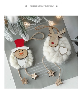 Details von gestrickten Schneemann- und Rentier-Anhängern mit Holzsternen am Tannenzweig