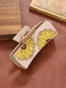 Macro shot of a matte cream shark hair clip with vibrant yellow sunflower patterns