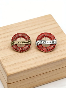 Macro view of Poppy Wreath brooches with Lest We Forget text on gold and silver banners