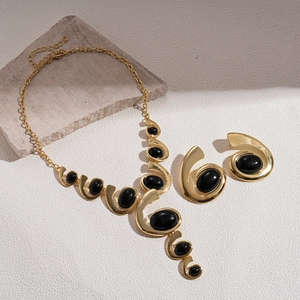 Retro gold necklace and earrings set featuring black oval gems and spiral curves