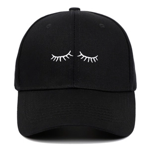 Close-up of white eyelash embroidery detail on black baseball cap with fine fabric texture