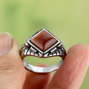 Macro detail of men's vintage titanium ring featuring a square brown goldstone gem