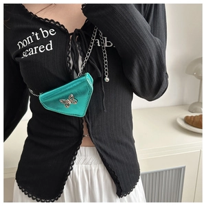 Détail d'un mini sac bandoulière triangulaire vert métallisé avec ornement papillon argenté