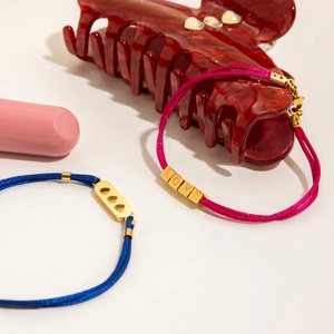 Détail de bracelets en corde tressée avec perles LOVE dorées et breloques en forme de cœur