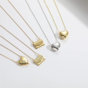 Set of gold and silver heart and envelope pendant necklaces on white background