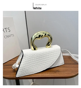 Detail of white crocodile embossed mini bag with irregular golden metal handle