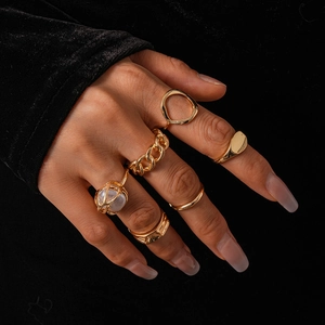 Detail of 12-piece gold geometric ring set worn on model with elegant black velvet background