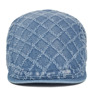 Close-up of diamond-quilted denim beret featuring distressed frayed seams and texture