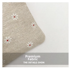 Close-up of woven straw fabric with white and red floral embroidery and texture