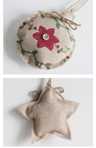 Detail of rustic linen Christmas ornaments with red flower embroidery and wooden button