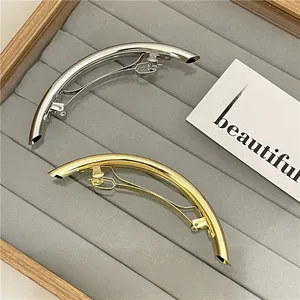 Polished silver and gold curved metal hair clips displayed on a velvet jewelry tray