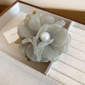 Détail de la pince à cheveux fleur en organza bleu avec perle d'imitation au centre