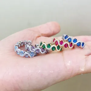 Close-up of four wavy stacking rings set with purple, green, pink, and blue gemstones