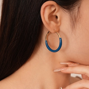 Close-up of gold and dark blue enamel geometric hoop earring worn by a model