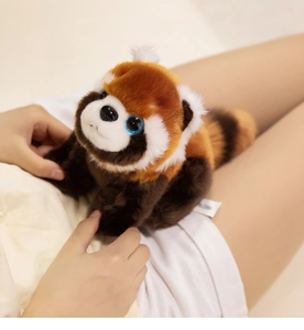 Macro shot of soft red panda plush toy with striped tail held by a model