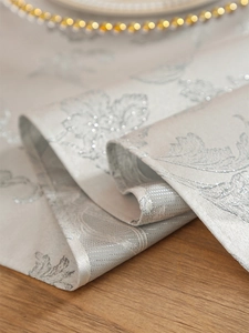 Detail of silver glittering floral pattern on beige thickened jacquard table runner