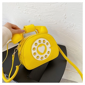 Close-up of retro yellow telephone crossbody bag featuring heart dial and spring cord detail