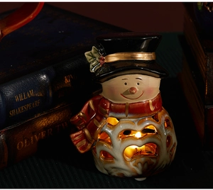 Close-up of a festive ceramic snowman candle holder with hollow cutouts for warm holiday light