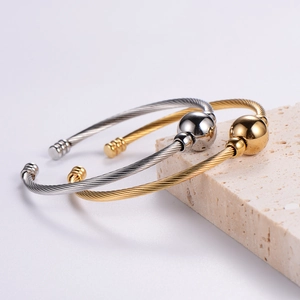 Adjustable cable wire bangle in gold and silver finish with steel bead accents