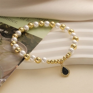 Détail d'un bracelet en perles dorées et blanches avec un pendentif goutte noir serti