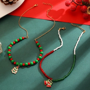 Détail du collier de Noël perlé avec cloches dorées et pendentif sapin vert