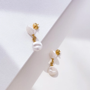 Detail of elegant gold-plated drop earrings featuring two white baroque pearls and studs
