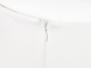 Detail shot of the high-quality invisible back zipper on this white mini dress